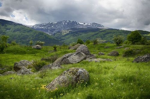 green mountains with rocks and white clouds